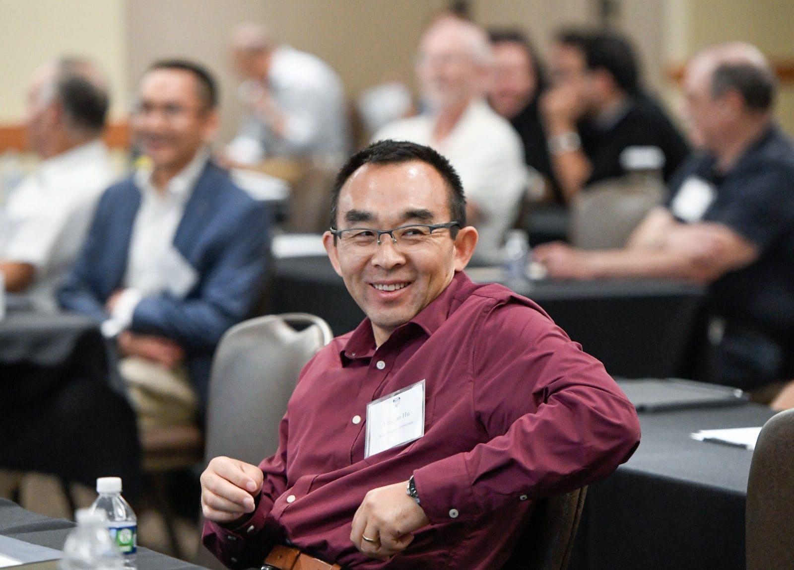 man in a button-down shirt smiling at a conference table