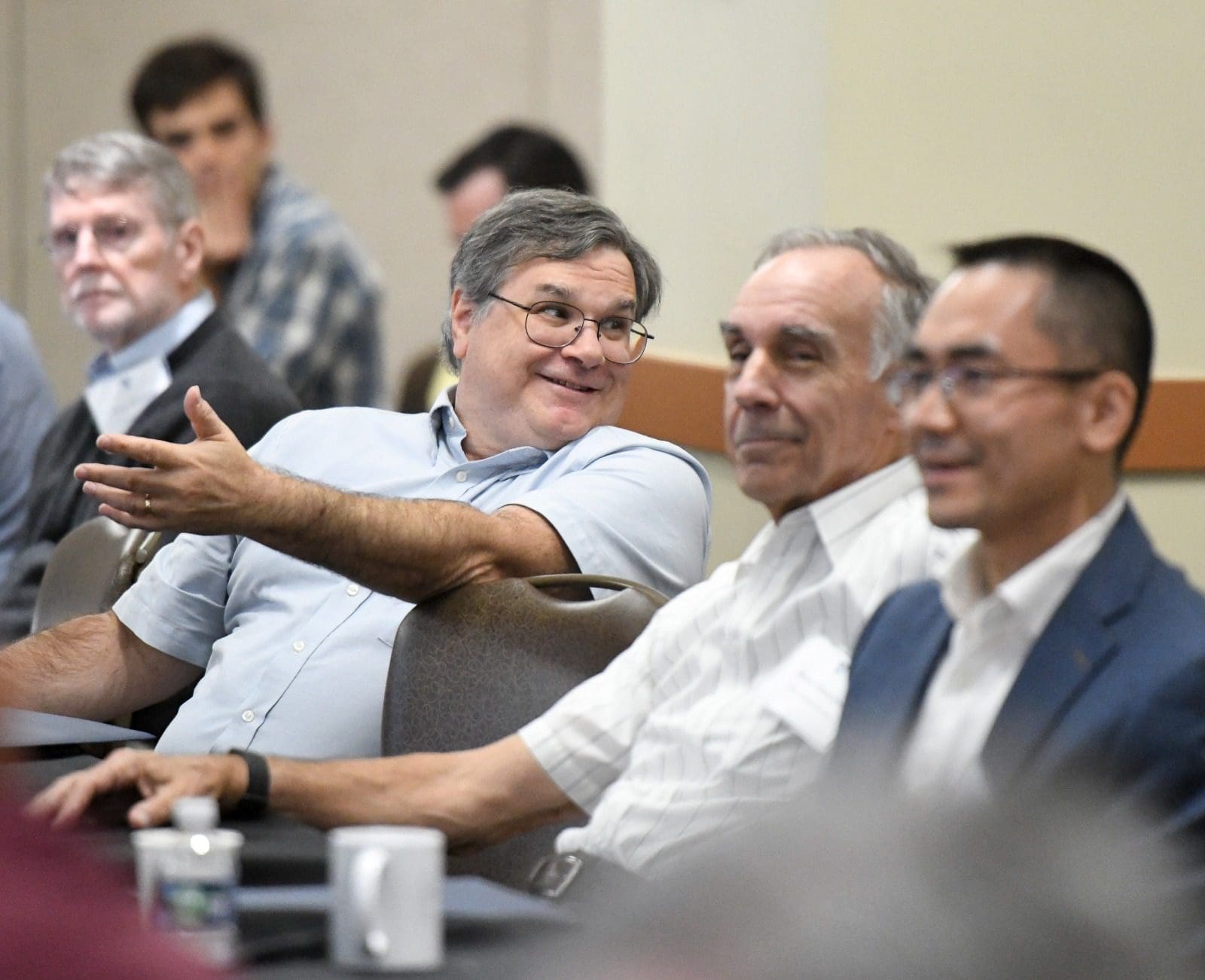 four men at a conference table smiling
